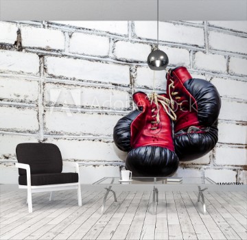 Bild på A pair of old boxing gloves hanging on white brick wall background